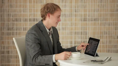 Young man sitting at table using touchpad and smiling at camera Stock Footage 34278403