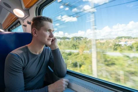 Young man sitting in the train and looks out the window Stock Photos