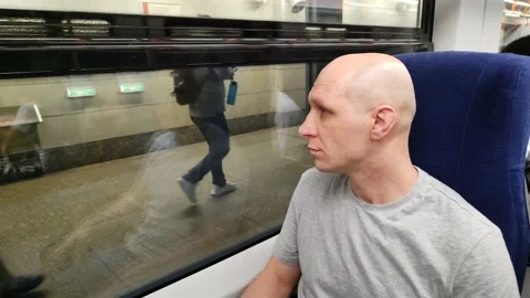 Young man sitting in train, looking out window and waving to people Video stock 201472325
