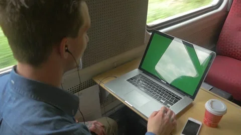 Young man sitting on the train using laptop with green screen Stock Footage