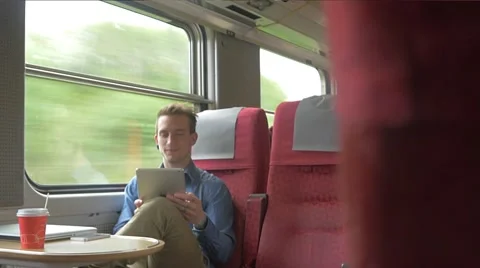 Young man sitting on the train while using his tablet Stockbeeldmateriaal 51832560