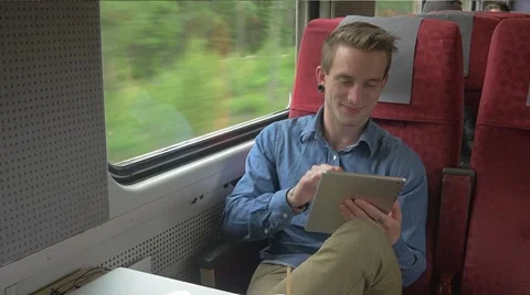 Young man sitting on the train while doing work on his tablet Stockbeeldmateriaal 51832565