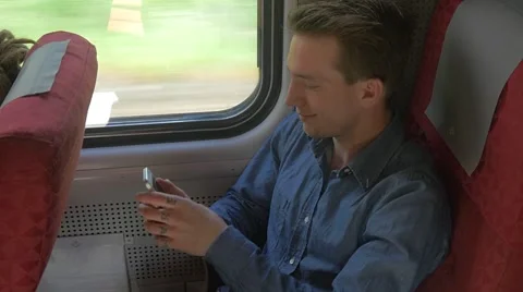 Young man sitting on the train while talking on his mobile Stockbeeldmateriaal 51832602