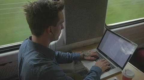 Young man sitting on the train while using a laptop to do work Stockbeeldmateriaal 51832629