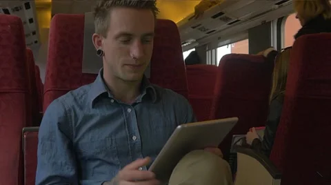 Young man sitting on the train while using tablet Stock Footage 51832678