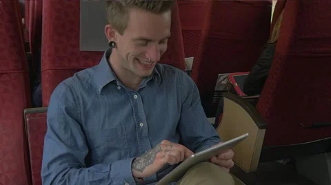 Young man sitting on the train while using tablet to do work Stock Footage 51832688