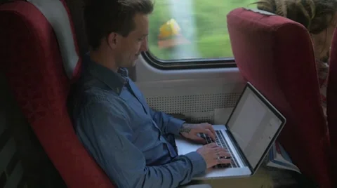 Young man sitting on the train while using a laptop Stockbeeldmateriaal 51832723