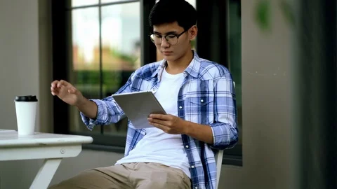 Young man sitting use tablet and drinking beverage Stock Footage 106550231