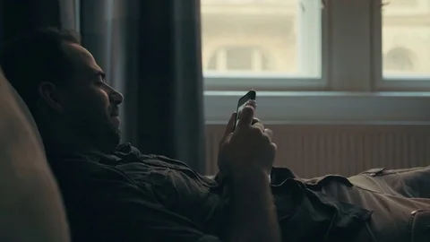 Young man sitting using his smartphone Stock Footage 76532650