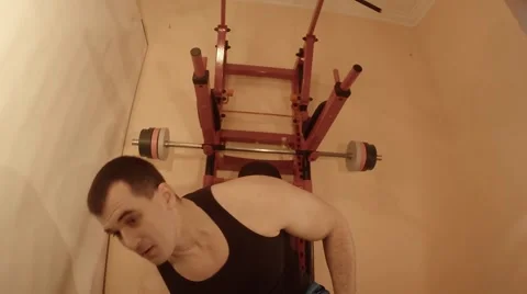 Young Man Sitting on a Wall Bars Doing Exercises With Dumbbells in the Room Stock Footage 62475450