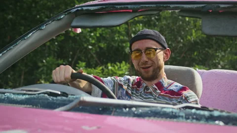 Young man sitting in wrecked pink convertible and confidently looks in camera Stock Footage 237166336