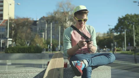 Young man with skateboard texting on cell phone in a city. Vídeo Stock 42990153