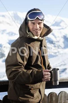 Young man in ski wear smiling at camera, holding glass Stock Photos