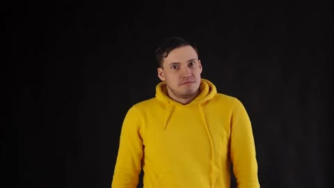 Young man slaps his cheeks on black background. Emotional guy does not control Stock Footage 150942446