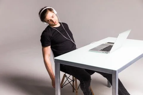 Young man sleep while wearing headphones and work on laptop on his office tab Stock Photos