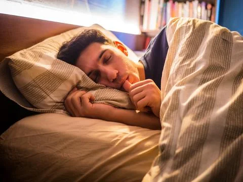 Young man sleeping on bed and sucking finger Stock Photos