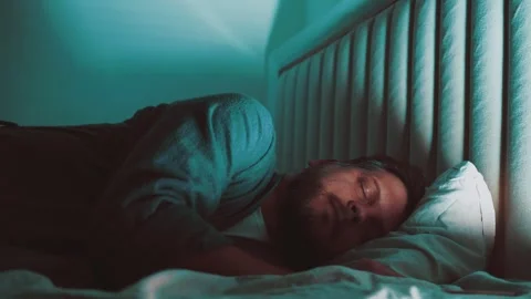 A young man sleeping in a bed at night Stock Footage 257690367