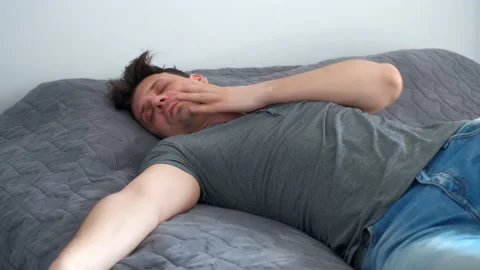 Young man is sleeping in bed wearing in jeans and t-shirt after party. Stock Footage 153012831