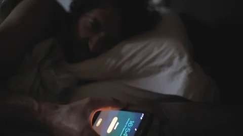 Young man sleeping in a bed woken by alarm on a smart phone 4K Vídeos de archivo 116048761
