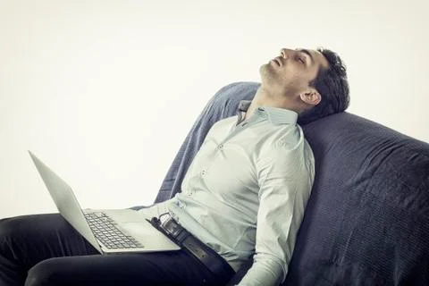 Young man sleeping with computer on couch Stock Photos