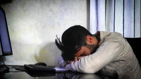 Young man sleeping at computer at home Stock Photos