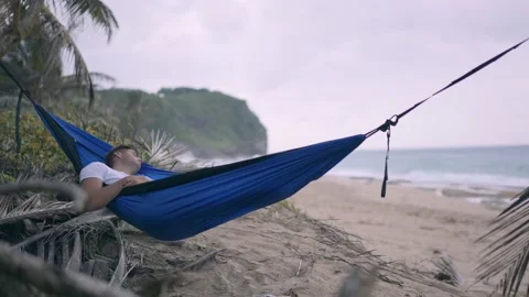 Young man sleeping in hammock on beach in Puerto Rico Stock Footage 157401900