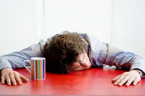 Young man sleeping, leaning against a table Stock Photos