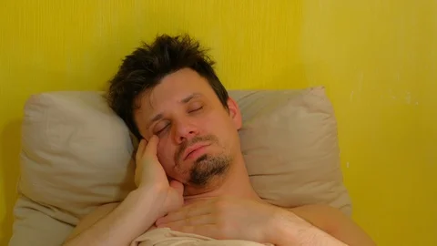 Young man is sleeping in reclining pose with hands on face and snores. Stock Footage 128705432