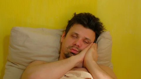 Young man is sleeping in reclining pose with hands on face and snores. Stock Footage 128952077