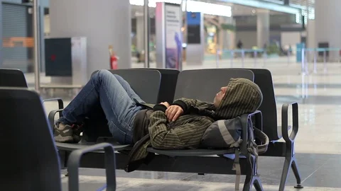 Young man sleeping while waiting the plane at airport passenger terminal Stock-Footage 98322122