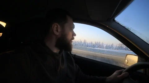 The young man slowly driving a car on a winter road. In winter, the majority of Stock Footage 97470153