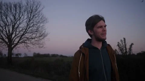The young man slowly walking down the road from his car in the evening Stock Footage 131009712