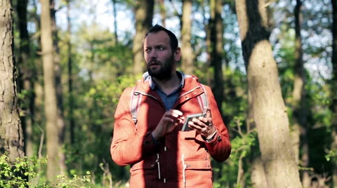 Young man with smartphone looking for direction with smartphone in the forest HD Stock Footage 49977170