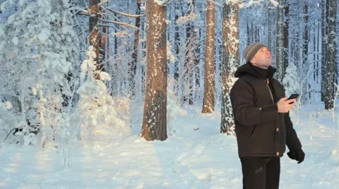 Young man with smartphone looking for direction in winter forest Video stock 59769694
