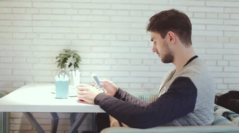 Young man with smartphone sitting in cafe Stock Footage 58644228