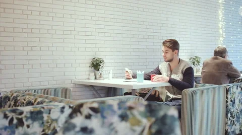 Young man with smartphone sitting in cafe, close-up Stock Footage 63049156