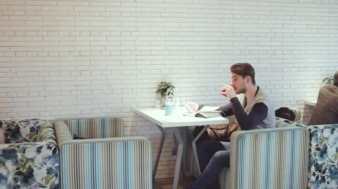 Young man with smartphone sitting in cafe Stock Footage 63065238