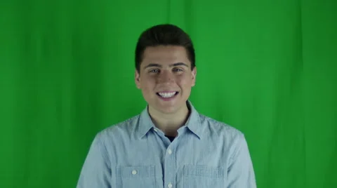 Young man smiles and hold hands up in glee in front of greenscreen Stock Footage 59088220