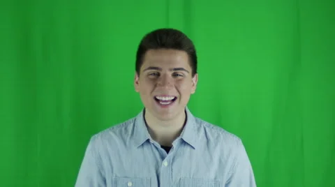 Young man smiles and hold hands up in glee in front of greenscreen Stock Footage 59088225