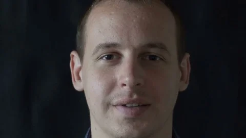 A young man smiles on a black background Video stock 76524292