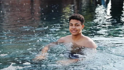 Young man smiles joyfully as he relaxes and enjoys summer day in a swimming pool Stock Footage 328160180
