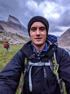 A young man smiles for a selfie while hiking in the Rocky Mountains Stock Photos