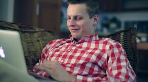 Young man smiling and looking at a laptop Stock Footage 48594631