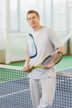 Young man smiling and posing with tennis racket indoor Stock Photos