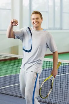 Young man smiling and posing with tennis racket indoor Stock Photos