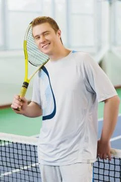 Young man smiling and posing with tennis racket indoor Stock Photos
