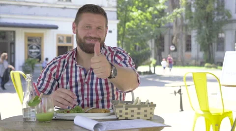 Young man smiling for camera and shows ok, during lunch. Vídeo Stock 67604193