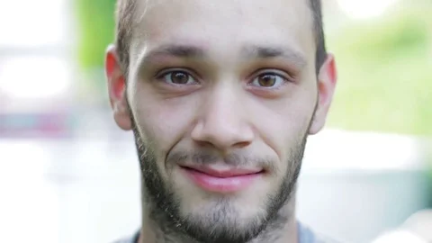 Young Man Smiling at Camera, Blurred Background Видео 76267990