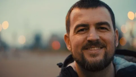 Young man smiling to camera at the evening city street. Video stock 84227878