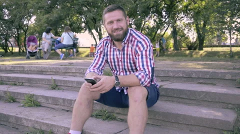 Young man smiling for camera, sitting on stairs. Slider and pan shot. 库存影片 67241589